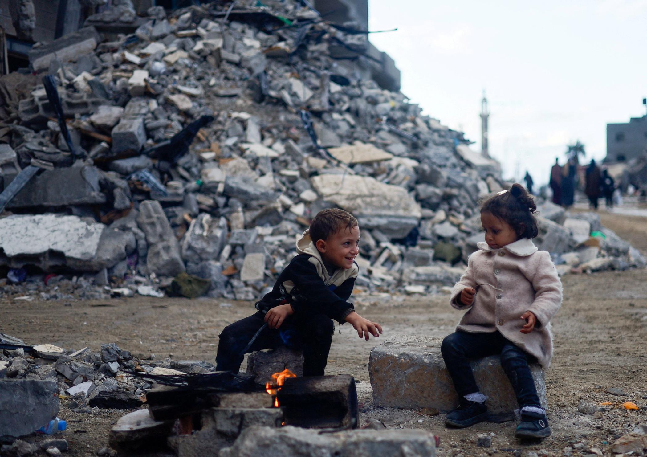 Palestinian children sit by the fire next to the rubble of a house hit in an Israeli strike during the conflict, amid a temporary truce between Hamas and Israel, Khan Younis, southern Gaza Strip, Nov. 27, 2023. (Reuters Photo)