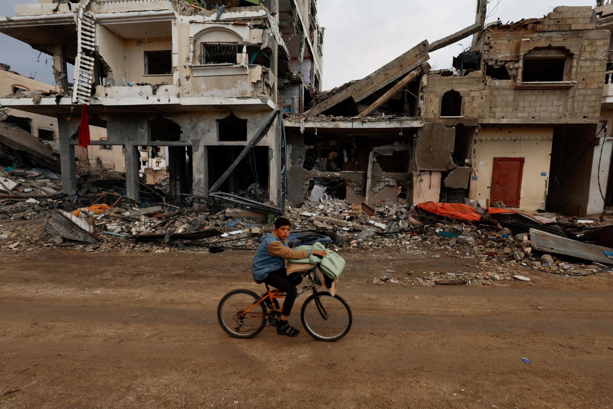 A Palestinian boy rides a bicycle next to the rubble of a house hit in an Israeli strike in Khan Younis, southern Gaza Strip, Nov. 27, 2023. (Reuters Photo)